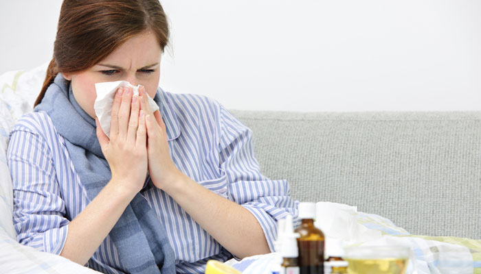 A woman blowing her nose during a common cold.
